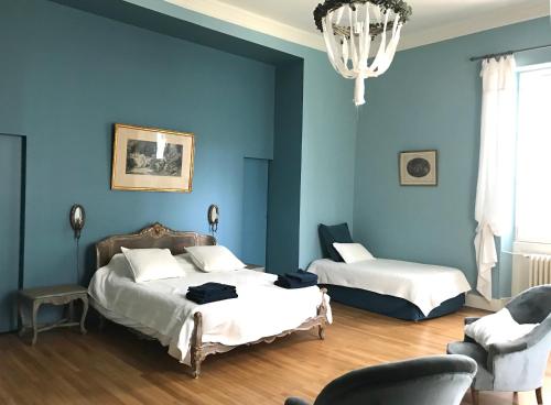 a blue bedroom with two beds and a chandelier at Château du Grava in Haux