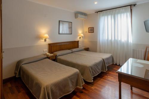 a hotel room with two beds and a window at Hotel Leku Eder in San Sebastián