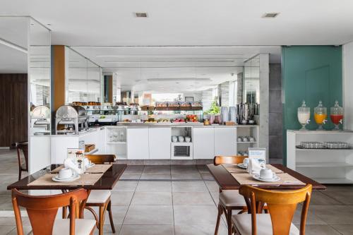 a dining room with tables and chairs and a kitchen at Citi Hotel Express Caruaru in Caruaru