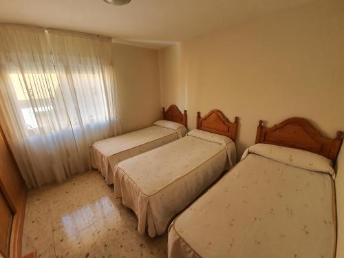 ポルトノボにある2 I Playa Baltarのベッド3台と窓が備わる客室です。