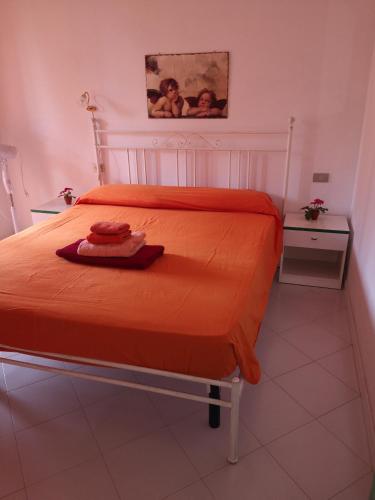 a bedroom with a bed with an orange bedspread at Sunny garden house in Villasimius