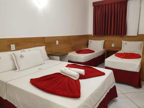 una camera con tre letti con coperte rosse di Pousada Santa Catarina a Cachoeira Paulista