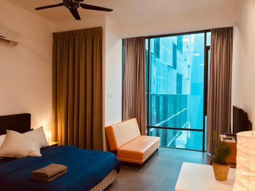 a bedroom with a bed and a chair and a window at Montana Suite 5, Empire Damansara in Petaling Jaya
