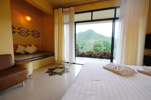 a bedroom with a bed and a large window at Hi-scene Resort in Suan Phung