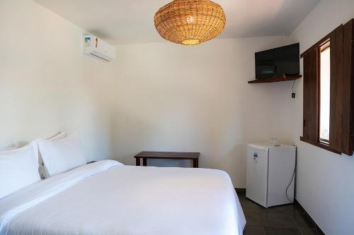 a bedroom with a white bed and a television at Trancoso Pousada in Trancoso
