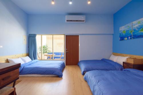 two beds in a room with blue walls at 夏天民宿 in Magong