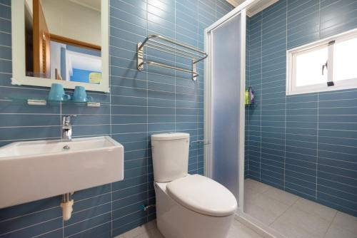 a blue tiled bathroom with a toilet and a sink at 夏天民宿 in Magong