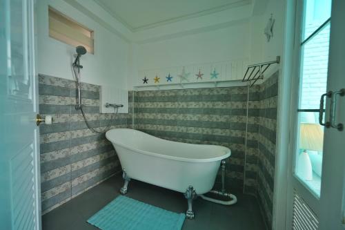 a white bath tub in a bathroom with tiled walls at DD Hut Koh Tao in Koh Tao