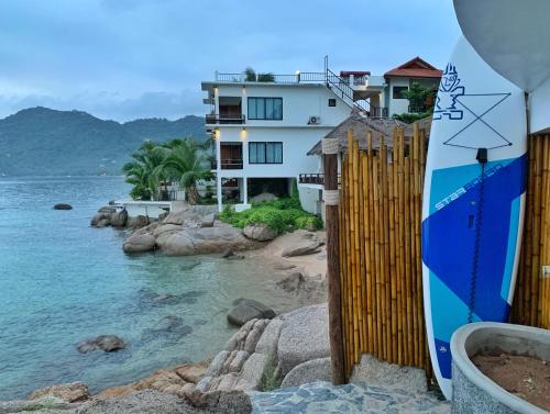 a surfboard leaning against a fence next to the water at DD Hut Koh Tao in Koh Tao