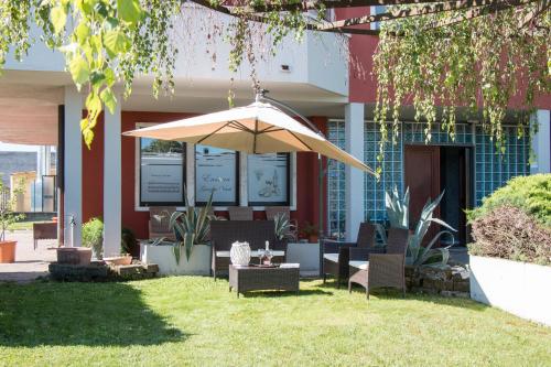 a patio with an umbrella in front of a building at Villa Boninsegna - Wine Enoteca Verdi - in Castel d'Azzano