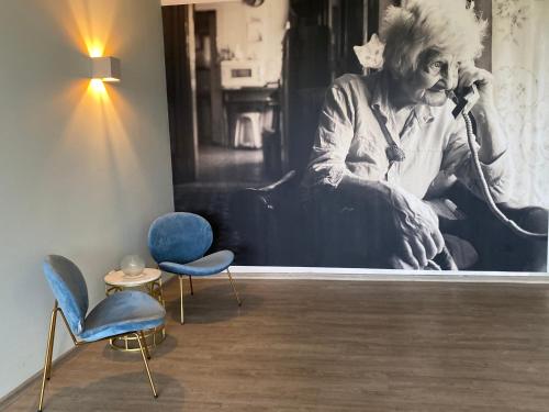 a room with chairs and a painting of a man talking on a phone at Das Hotel Ostseeblick in Lütjenburg