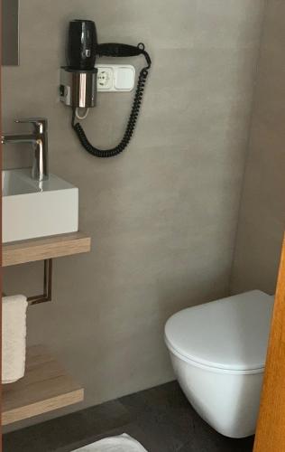 a bathroom with a toilet and a phone on the wall at Haus Flexen rooms & apartments in Stuben am Arlberg