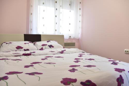 a bedroom with a bed with purple flowers on it at Berlin apartment in Brčko