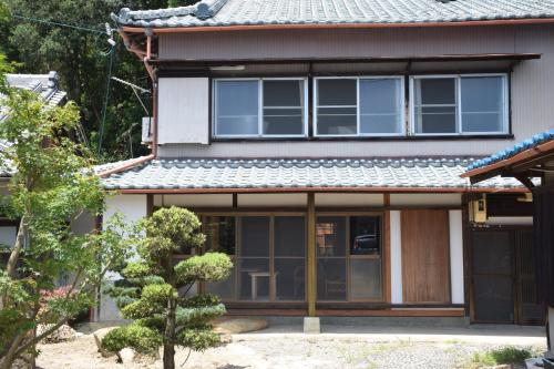 uma casa com uma porta da frente e uma árvore em ゲストハウス三軒家 em Shirahama