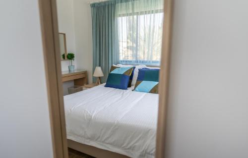 a bedroom with a bed with blue pillows and a window at Fig Tree Beach Houses in the heart of Protaras in Protaras