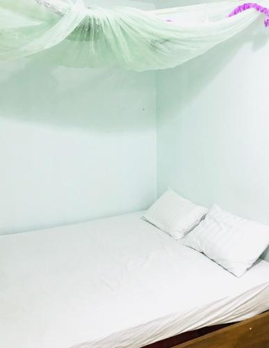 a white bed with white sheets and pillows at Nhi Lo Home Stay in Tân Hiệp