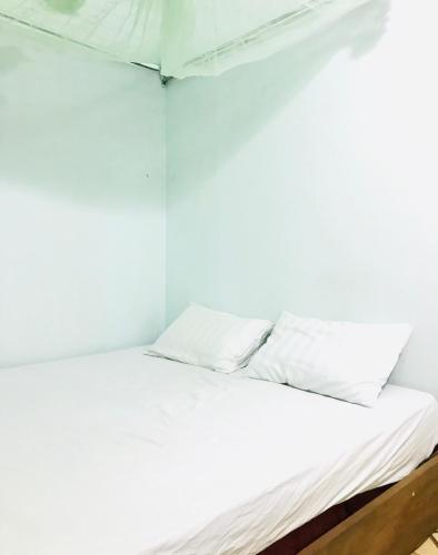 a bed in a room with white sheets and pillows at Nhi Lo Home Stay in Tân Hiệp