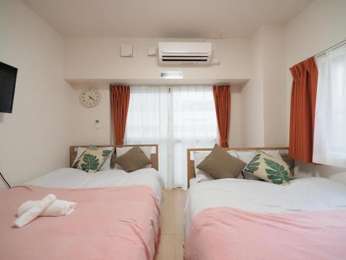 a room with two beds and a window at Daruma apartment 403 in Naha