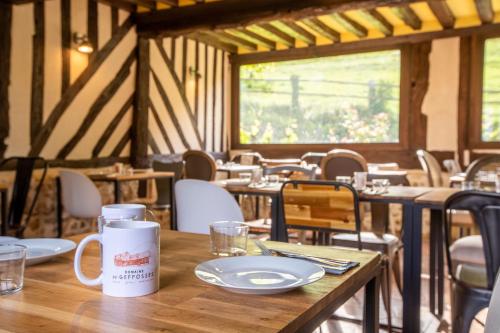 una mesa de madera con una taza y platos. en Domaine de Geffosse, en Pont-lʼÉvêque