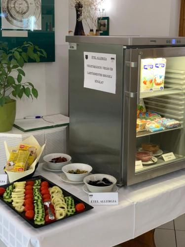 a display of food on a counter next to a refrigerator at Hotel Club Tisza in Lakitelek
