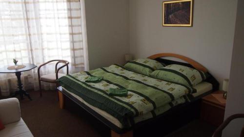 a bed in a bedroom with a table and a window at Penzion Jany in Luhačovice