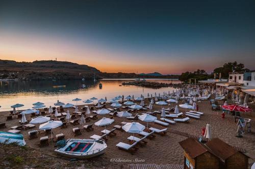 a beach with a bunch of chairs and umbrellas at Lindos Villa Agape in Líndos