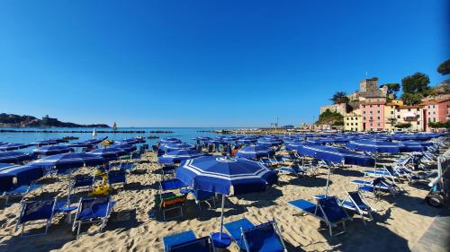 a beach filled with blue chairs and umbrellas at COMODO AL MARE in Lerici