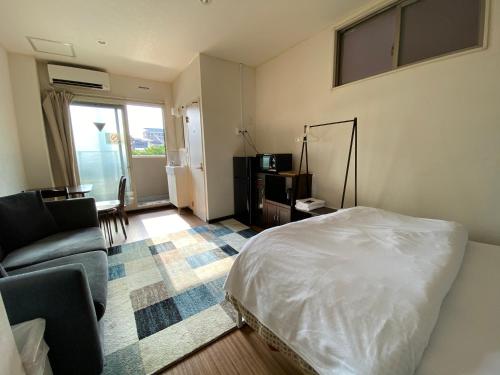 a bedroom with a bed and a living room with a couch at JAM Hostel Kyoto Gion in Kyoto