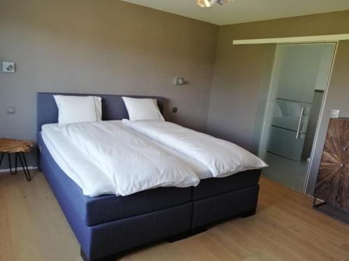 een bed met witte lakens en kussens in een kamer bij La Roseraie in Stavelot