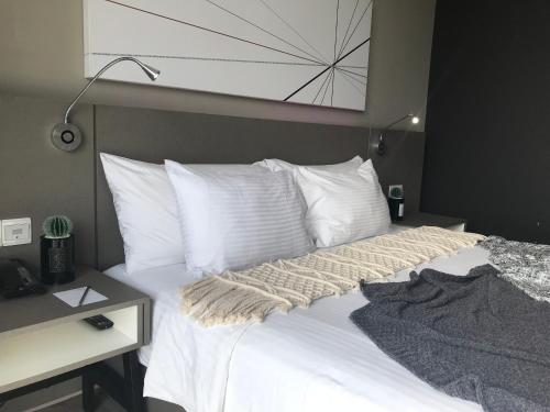 Schlafzimmer mit einem Bett mit weißen Kissen und einem Schreibtisch in der Unterkunft Lux Hotel Room in Damansara Perdana in Damansara Perdana