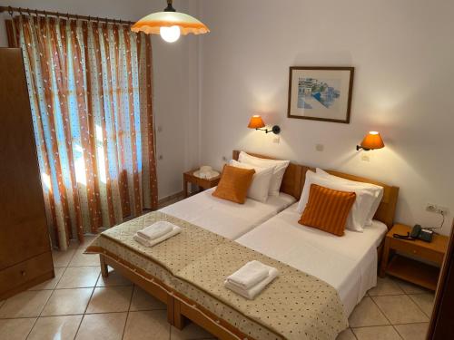 a bedroom with a bed with white sheets and orange pillows at Thalina Hotel in Marathokampos