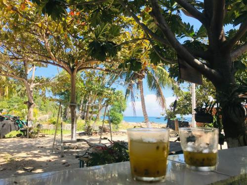 two drinks sitting on a table in front of the beach at Nhi Lo Home Stay in Tân Hiệp