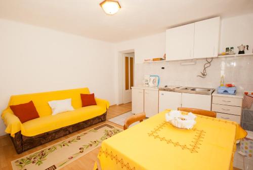 a living room with a yellow couch and a kitchen at Apartments Katarina in Baška