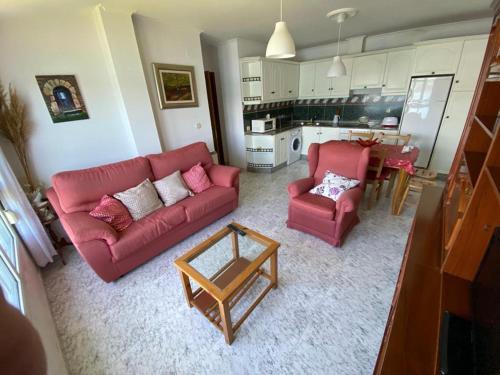 sala de estar con 2 sofás rojos y cocina en apartamento con vistas al mar y la montaña, en Santa Marta de Ortigueira