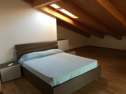 Un dormitorio con una cama en una habitación con techos de madera. en Apt 23 Residence delle Rose, en Peschiera del Garda