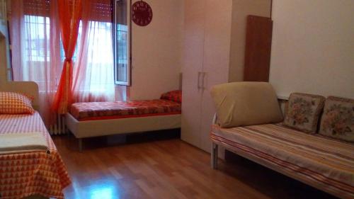 una camera con due letti, un divano e una finestra di Cara Revello a Milano