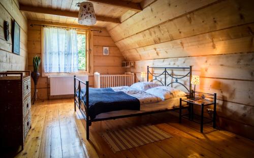 a bedroom with a bed in a room with wooden walls at Glisne 69 in Mszana Dolna