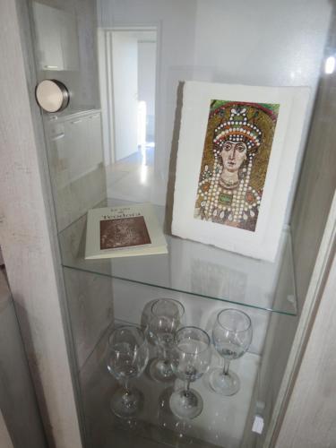 a glass shelf with wine glasses and a picture at Teodora Apartment in Ravenna