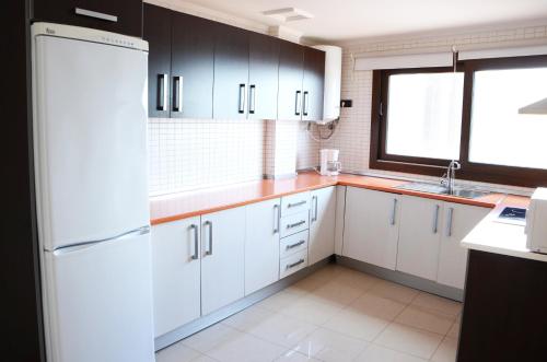 La cuisine est équipée de placards blancs et d'un réfrigérateur blanc. dans l'établissement Cotillo Ocean View, à El Cotillo