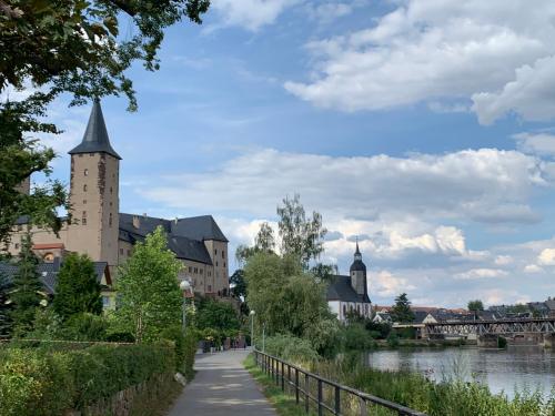 a walkway next to a river with a building at Ferienwohnung am Schloss Rochlitz in Rochlitz