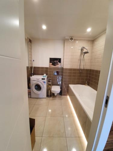 y baño con bañera y lavadora. en Apartament Lux, en Koszalin