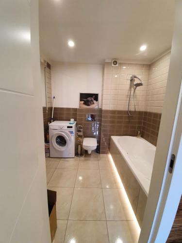 a bathroom with a tub and a washing machine at Apartament Lux in Koszalin