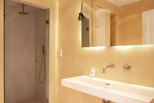 a bathroom with a sink and a shower with a mirror at The Little Townhouse in Amsterdam