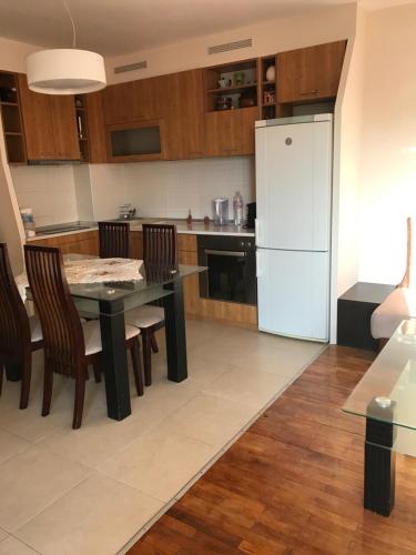 a kitchen with a table and a white refrigerator at Apartament Sunny, Варна- център in Varna City