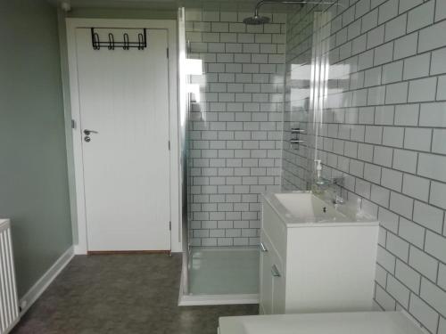 une salle de bain blanche avec un lavabo et un miroir dans l'établissement Old Station House - Kilfillan Cottage, à Garlieston