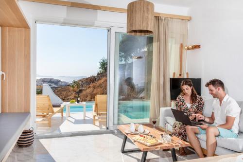 a man and a woman sitting on a couch in a living room at Nèsoi Villas Naxos in Naxos Chora