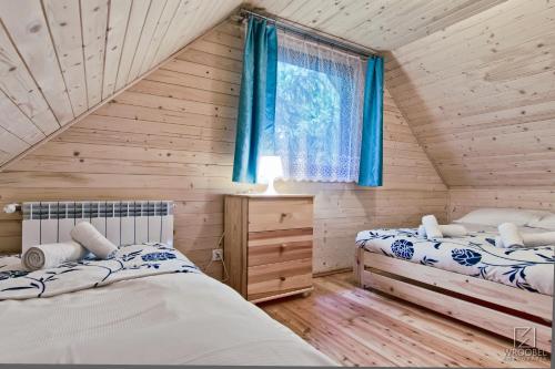 two beds in a log cabin bedroom with blue curtains at Domki Skiba Szaflary in Szaflary