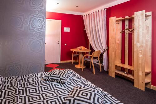 a red bedroom with a bed and a table at Abzali Hotel and Restaurant with self check-in in Ādaži