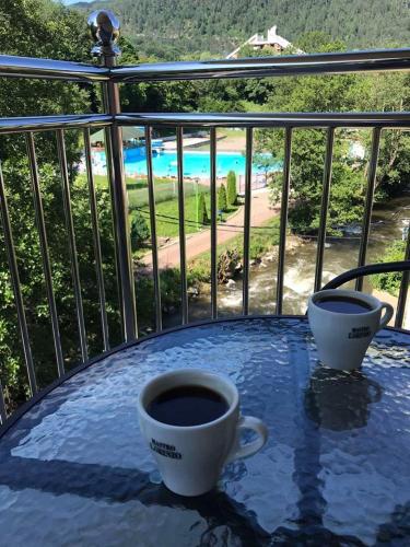 two cups of coffee sitting on a table on a balcony at Apartmani & SPA Matin Breg in Jošanička Banja