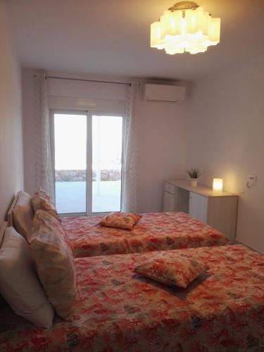a bedroom with two beds and a large window at Bouganville apartment Stegna in Archangelos